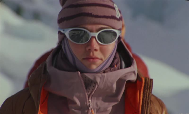 Two people walking dressed in winter clothes wearing protective glasses in a snowy environment