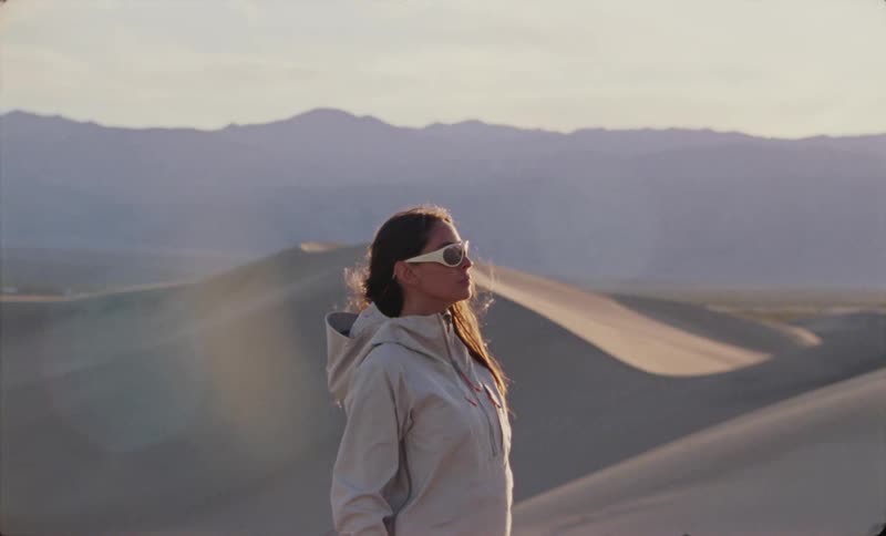 A woman standing in the desert embracing the serene sand dunes