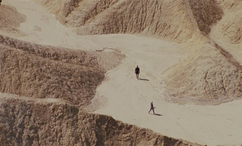 Top view of two people walking through desert mountains