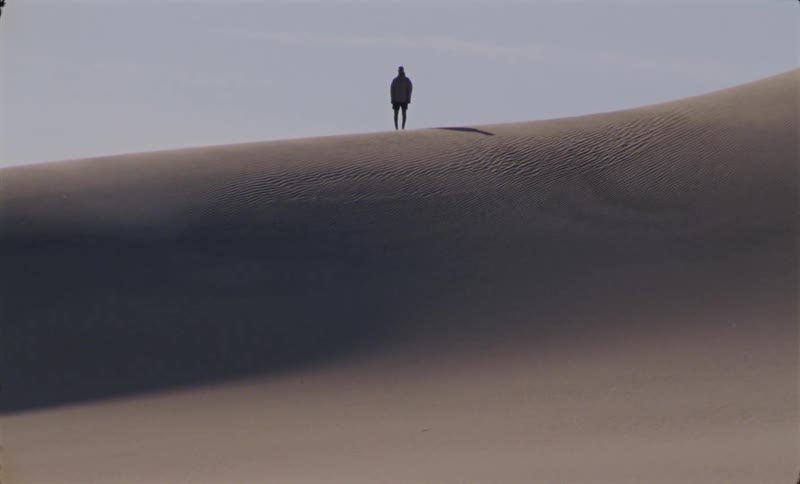 Person standing still on top of a sand dune
