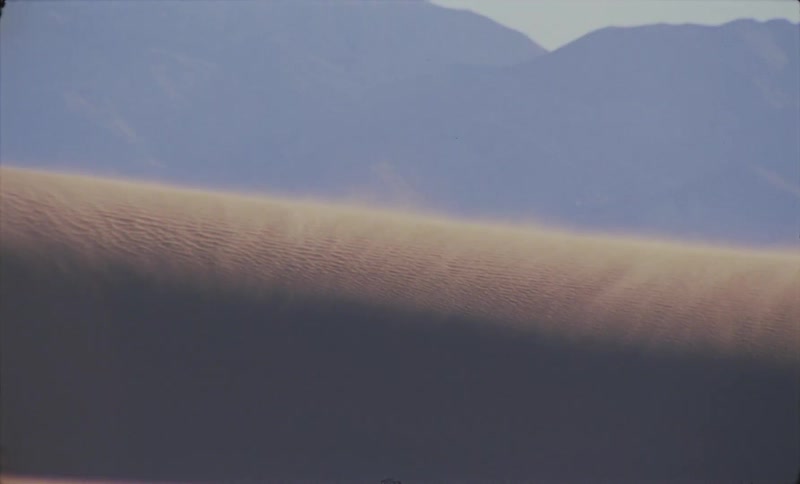 Landscape of a dune in the desert and the silhouette of mountains in the background