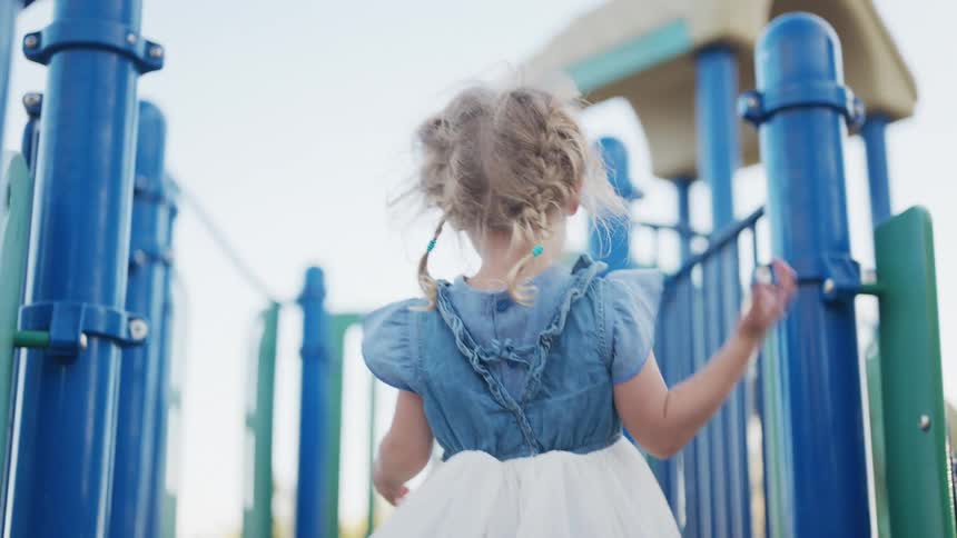 Little blonde girl dancing happily in a playground