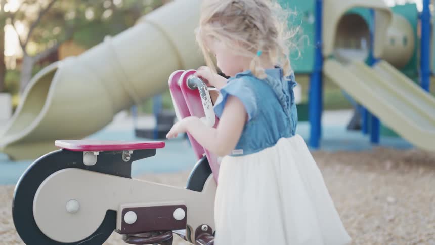 Little blonde girl playing in a playground during the day