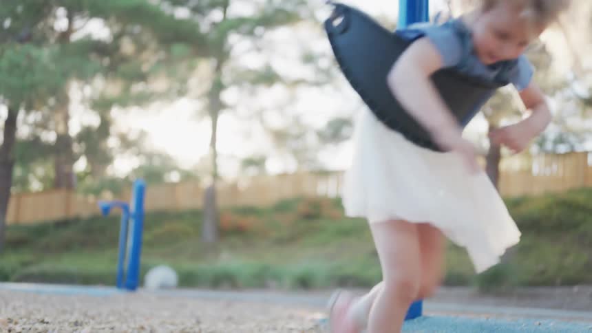 Little girl in a playground playing on a swing