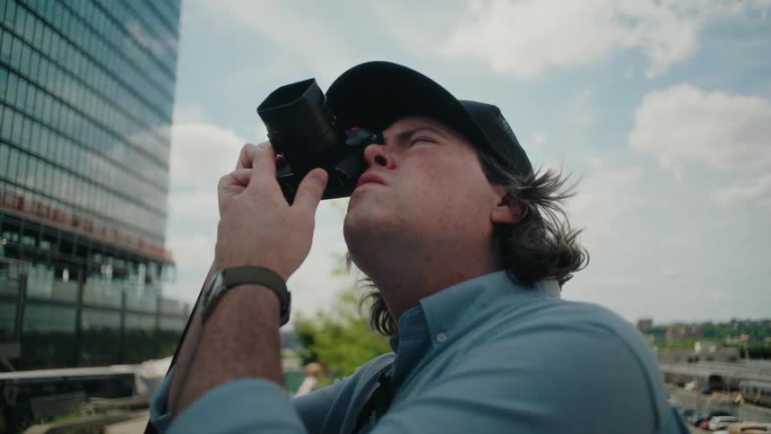 Portrait of a male photographer using a camera pointing upwards