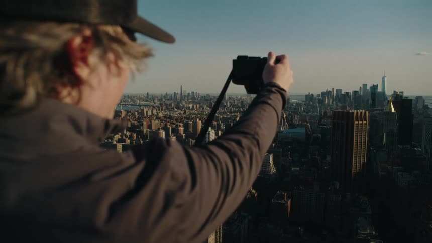 Photographer using a professional camera on the terrace of a building with a panorama of a metropolis