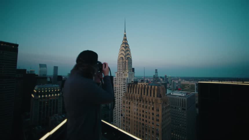 Man taking a picture of the chrysler building in new york city at dusk