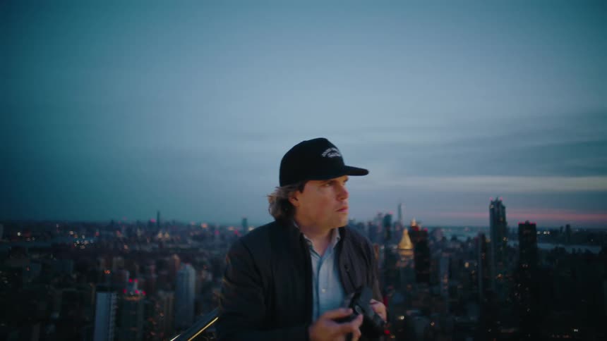 Man in a cap with a camera on the terrace and the background of a metropolis