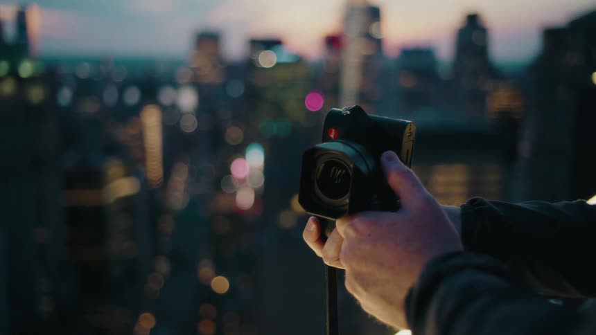 Hands holding a camera poised for a cityscape shot during twilight
