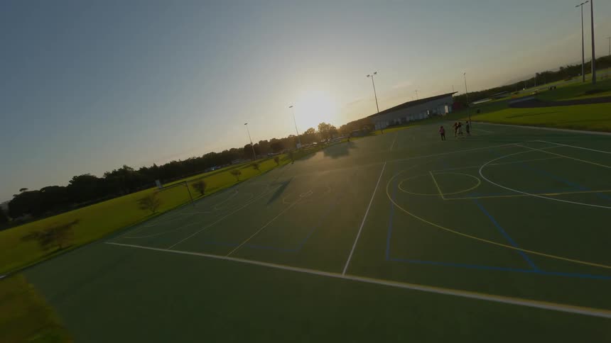 A clip of a basketball court shot with an FPV drone during sunset.