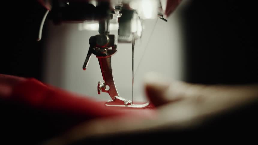 A person uses a sewing machine to stitch fabric