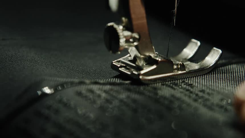 A closeup view of a sewing machine stitching black fabric