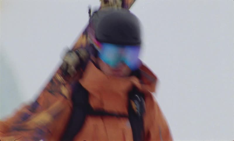 Skier carries his skis while hiking across the snow during a winter day