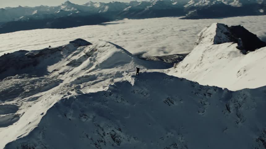 Person on a cliff of a snowy mountain peak