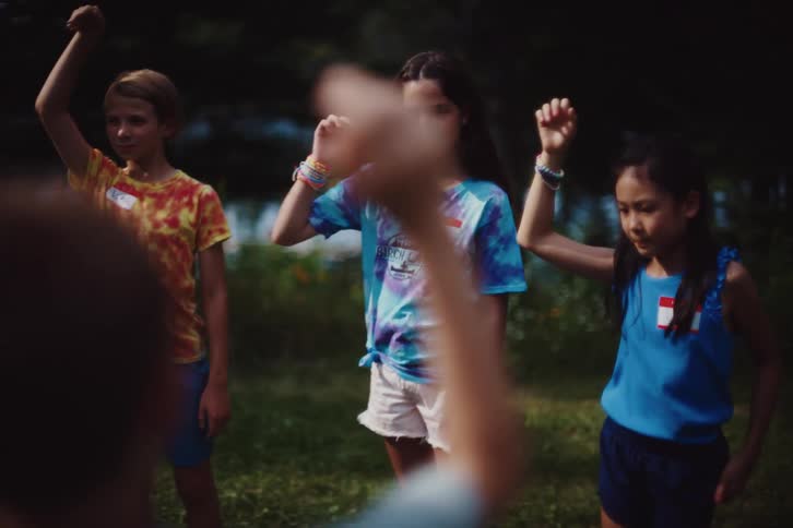 A group of children engaged in an outdoor activity with their arms outstretched appearing to play or interact with one another in a cheerful and dynamic setting