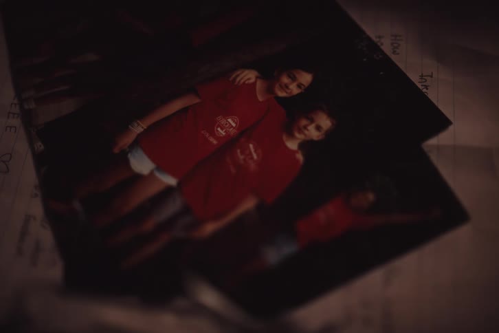 A person puts a photograph of two girls in matching red tshirts and then unfolds a letter