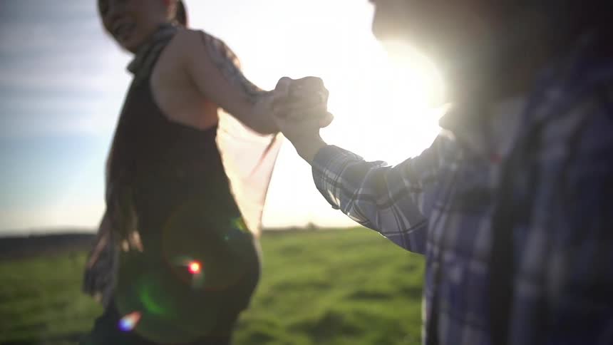 Woman and child running down field on a sunny day