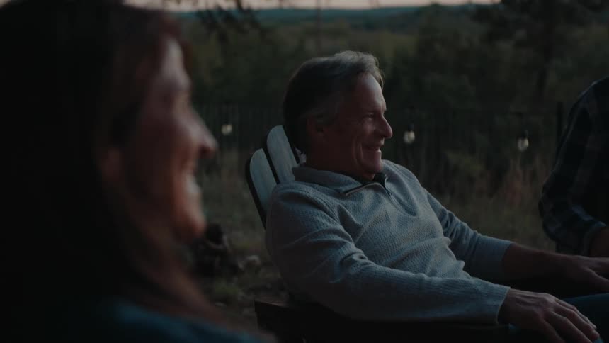 Friends enjoying laughter and conversation outdoors at dusk