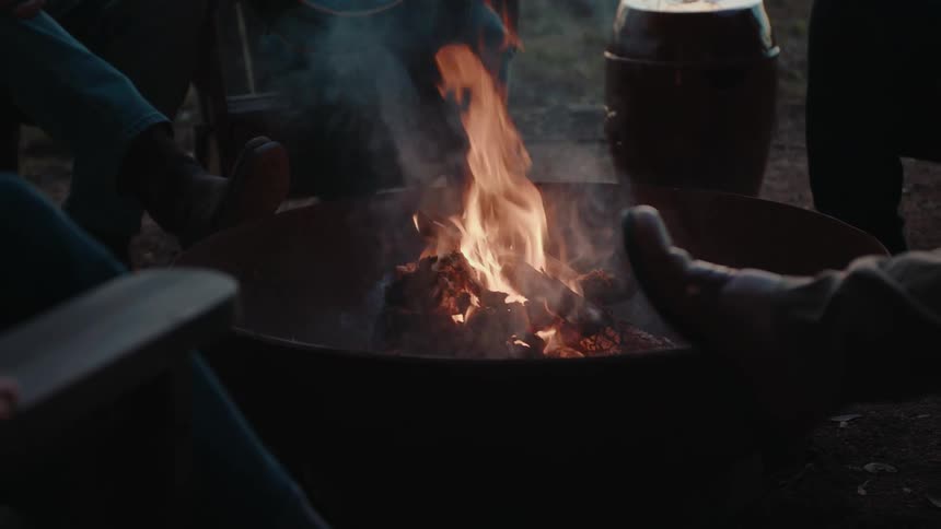 Group of people sitting on a chair around a campfire
