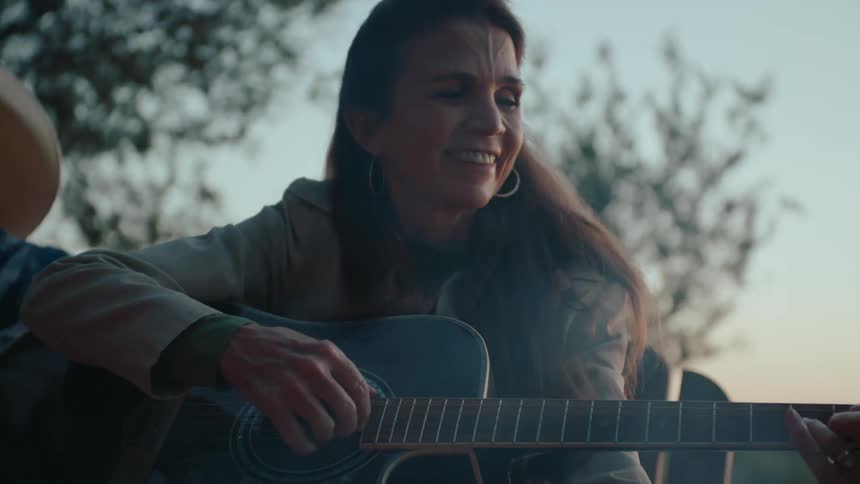 Woman sitting and happy playing guitar