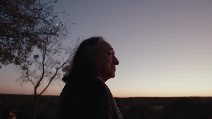 A clip of an elderly Native American man looking to the horizon at sunset