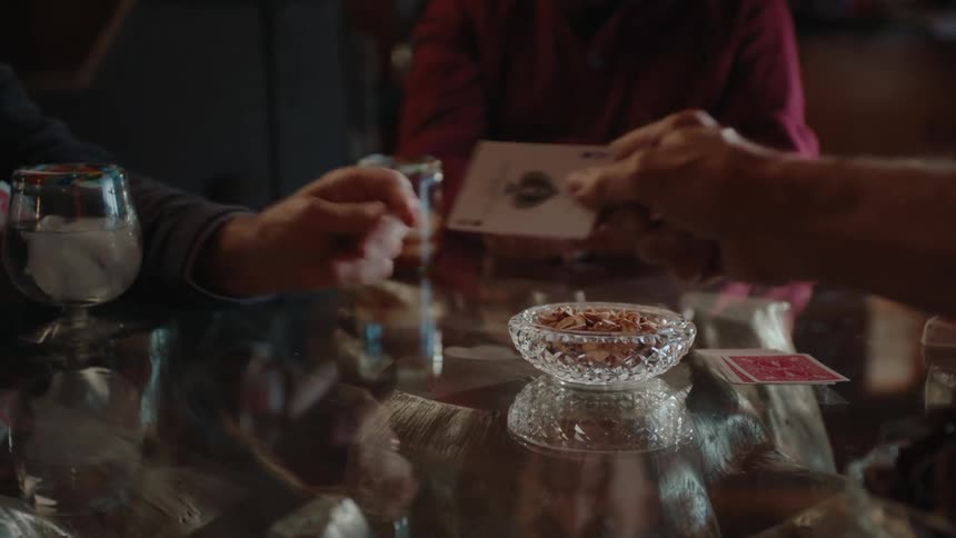 A closeup of hands exchanging cards in a friendly game around a glass table