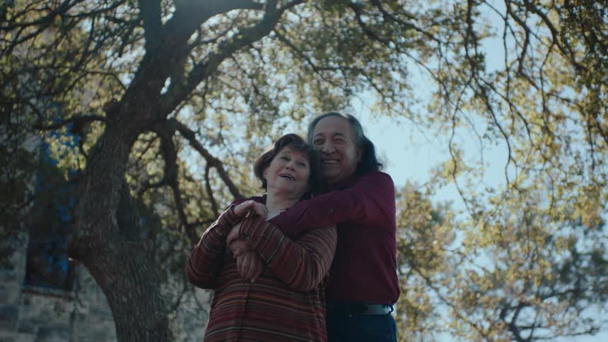 A happy couple embracing under a tree in the countryside