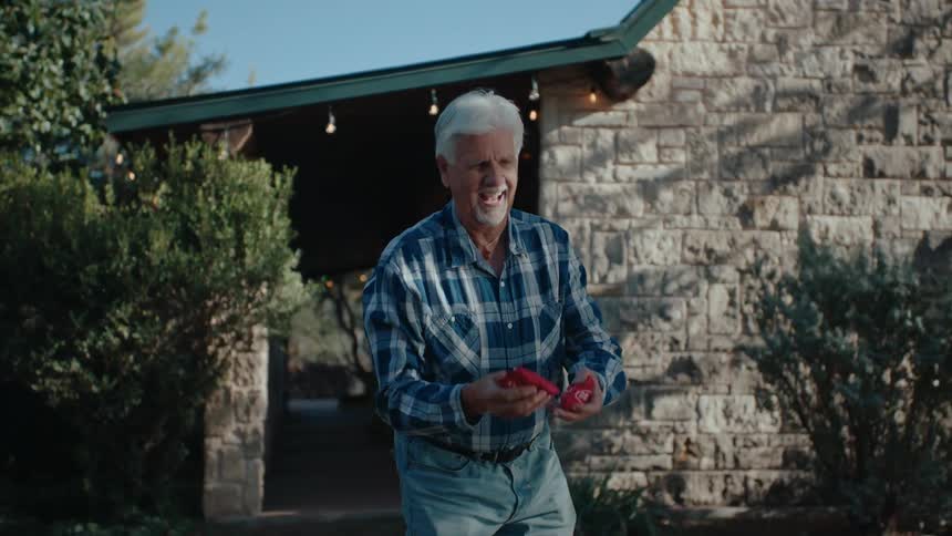 A man plays a game of outside a stone house in bright daylight