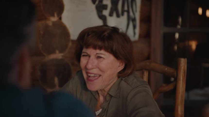 Woman laughs during a conversation with a man at a table outdoors