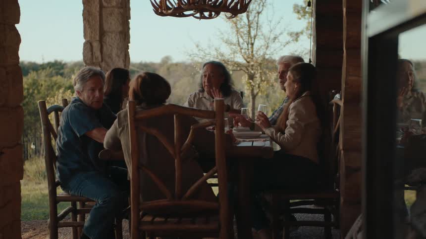 Family sitting at a table eating and talking in an outdoor area of the house