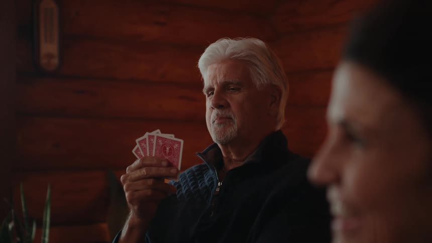 An elderly man enjoys a card game with a bright smile