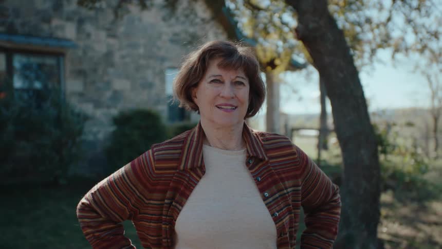 Smiling woman standing in front of a tree in her yard