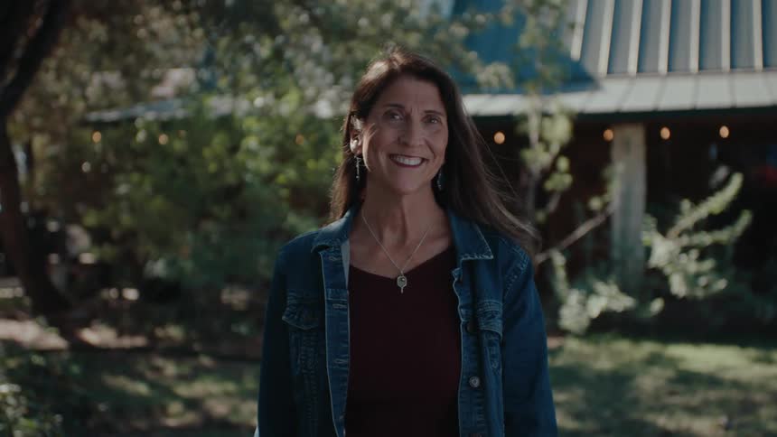 Portrait of an older woman in her backyard with garden smiling happily