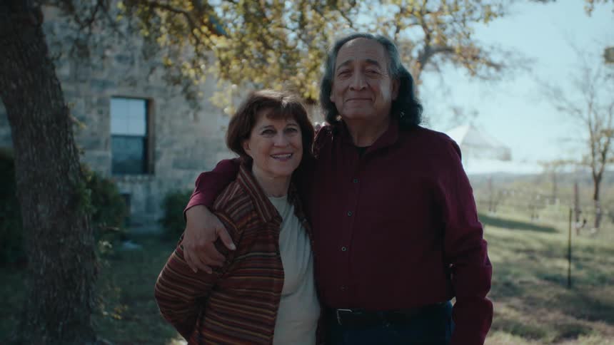 Elderly couple in a backyard with trees hugging each other romantically