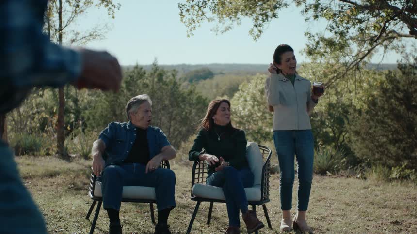 A family gathering in a large rural backyard playing games and relaxing
