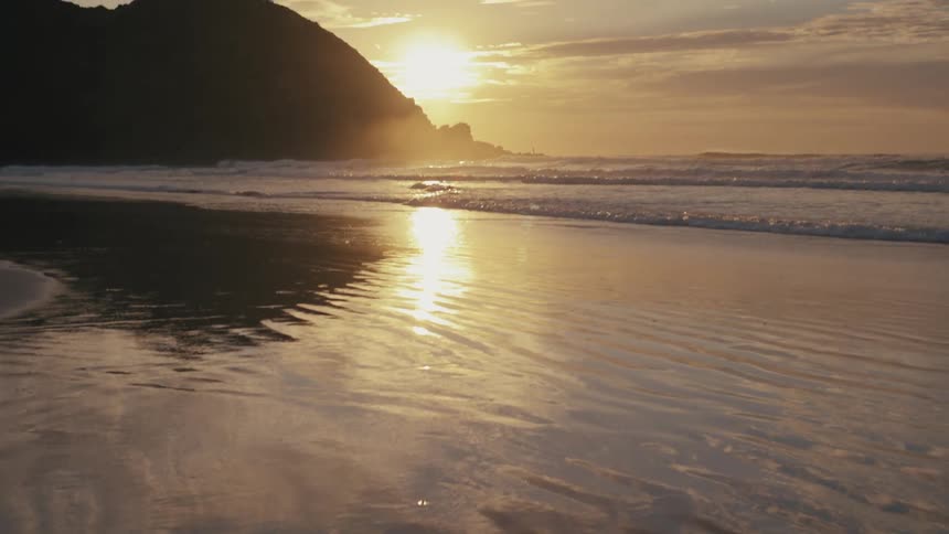 Beach next to a cliff outdoors during sunset