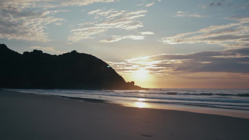 Landscape of the sea and the sand of the beach with the sunrise on the horizon