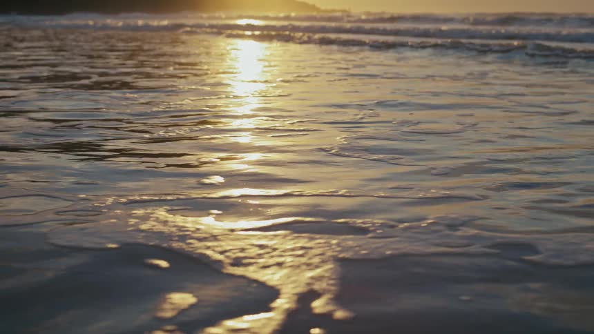 Calm waters of a beach with the sun on the horizon