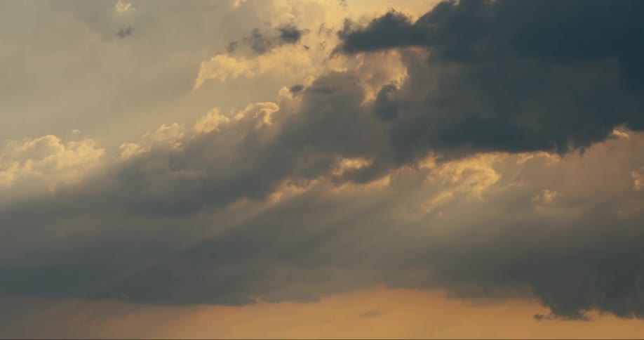 A dramatic sky with a mix of dark and light clouds with sunlight breaking through the clouds