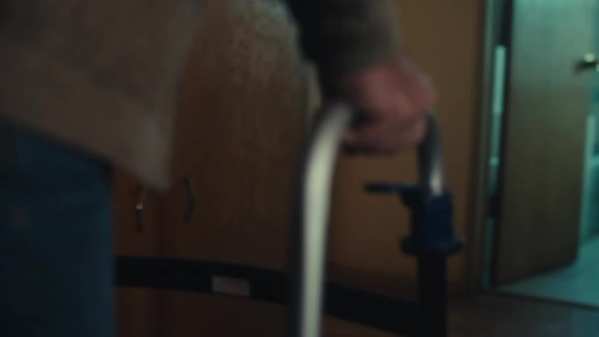 A man is walking in his home with a walker