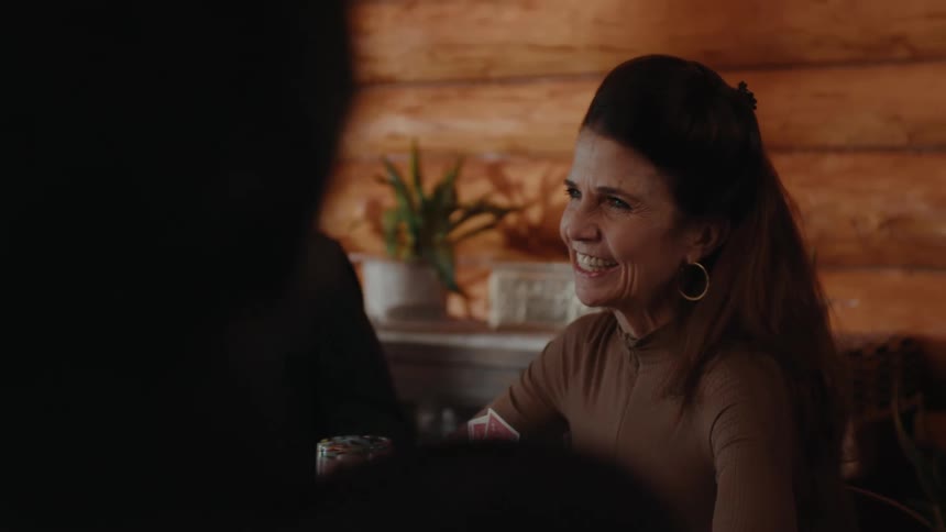 A happy couple sitting at a table playing cards with friends at a wooden cabin
