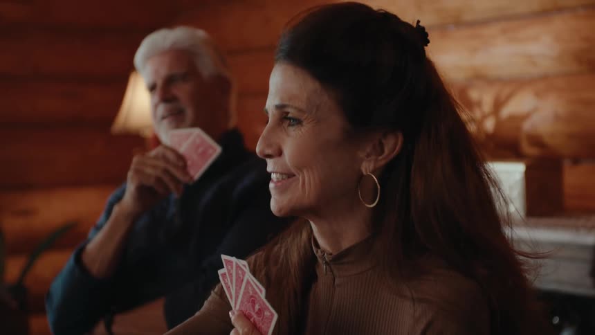 Group of people sitting at a table indoors playing cards