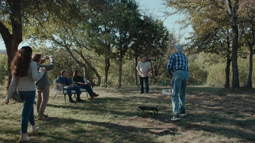A family gathering in a large rural backyard playing games and relaxing