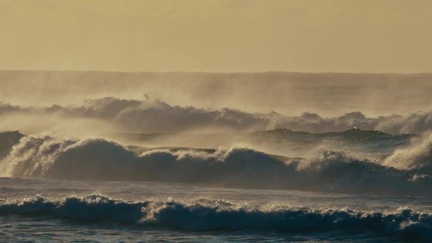 Strong ocean waves on a morning with a golden sky