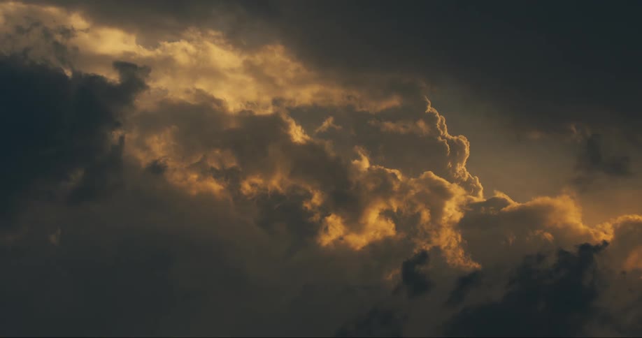 A dramatic sky with dark clouds illuminated by golden sunlight