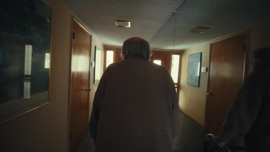 Elderly man walking down a hallway towards the door