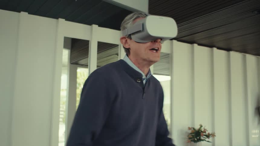 A man wearing a virtual reality headset playing video games at home