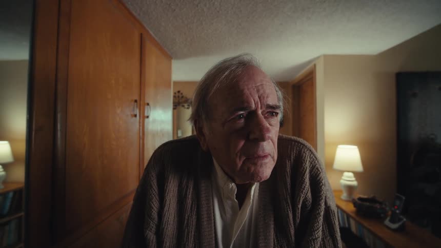 The face of an elderly man who is standing looking straight ahead and he is looking lost and then he looks and walks to his right