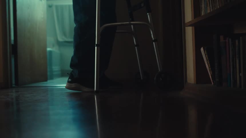 A persons legs are visible walking beside a walker resting on a polished floor
