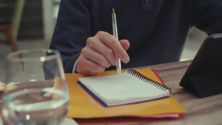 Man sitting at a table in front of a tablet and holding a pen